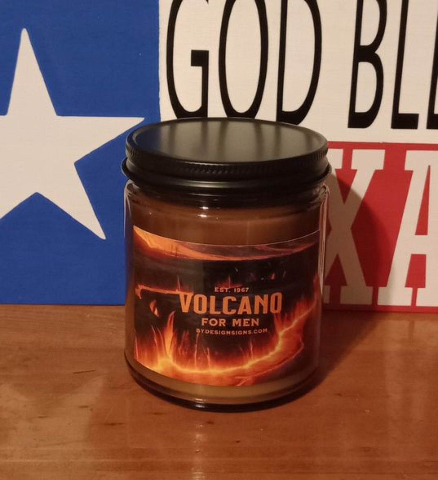 Image of a 9oz Dark Glass Jar Wood Wick Scented Candle with the image of Lava pouring over a Volcano and the words Volcano for Men written on it.