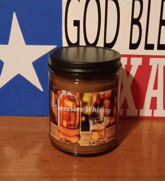 Image of a 9oz Dark Glass Jar Wood Wick Scented Candle with the image of a bottle of Whiskey a glass of ice filled with Whiskey and the words Tennessee Whiskey written on it.